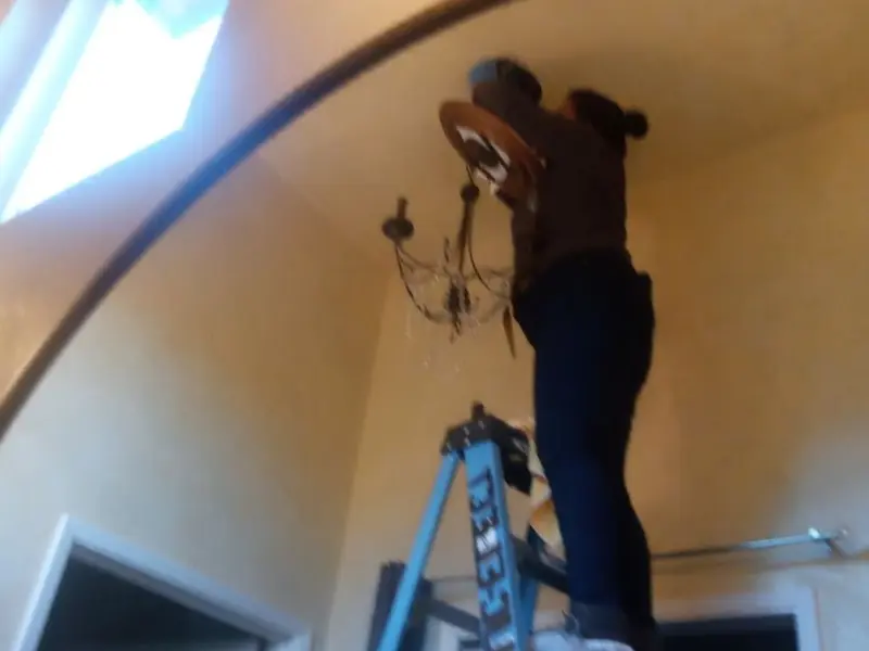 Electrician installing a chandelier in a Tucson Mountains residence